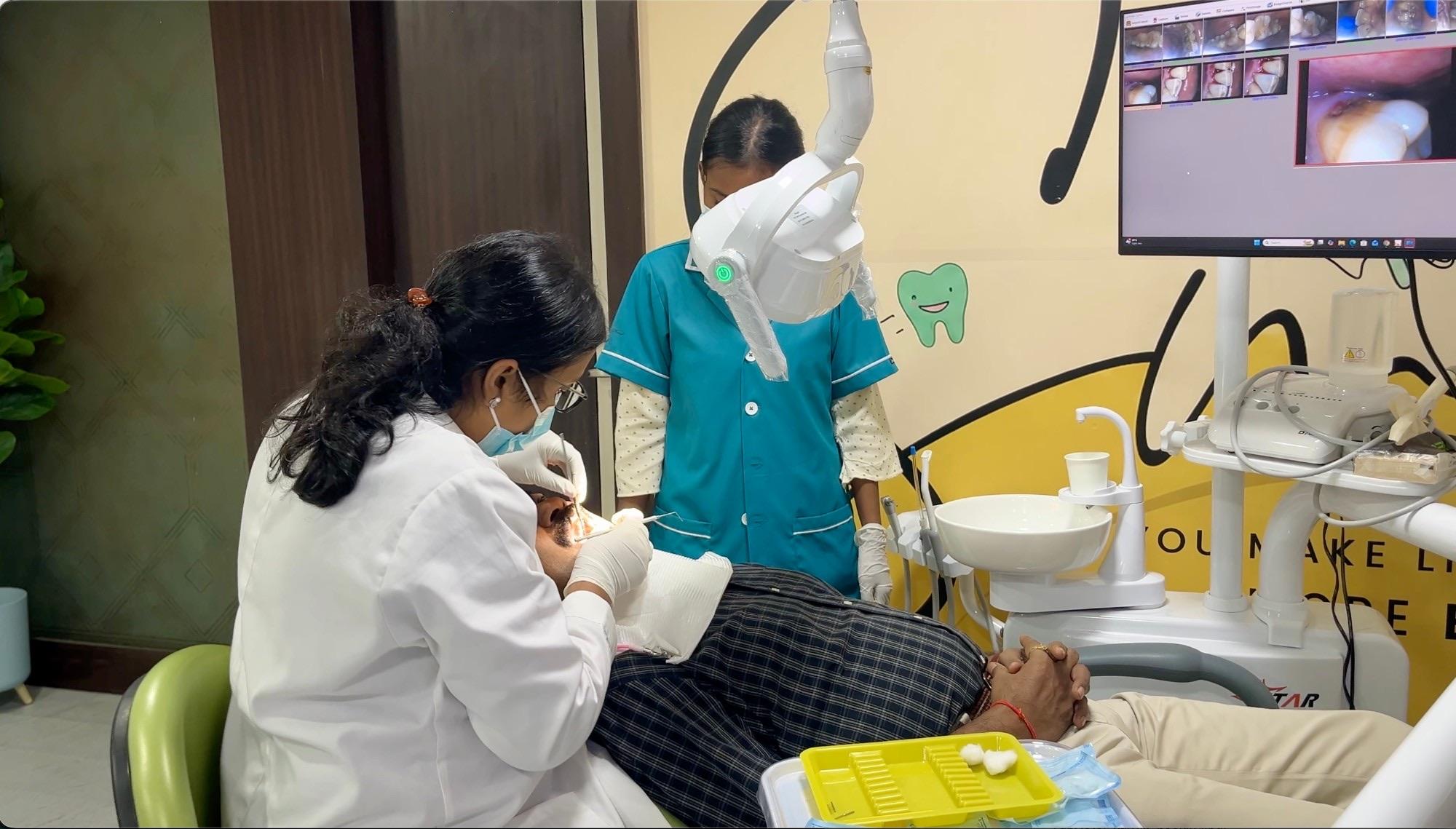 Dr. Ananya examining a patient in the treatment chair, intraoral camera images on the screen beside her, at White Oak Dental Studio, Ranchi