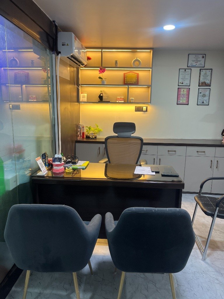 Doctor's consultation room with desk, patient seating, degrees on the wall and treatment planning models at White Oak Dental Studio, Ranchi