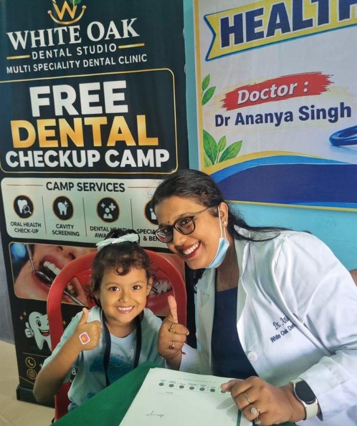 Dr. Ananya giving a thumbs-up with a smiling student at the White Oak free dental check-up camp, Sacred Child Academy, Kokar, Ranchi