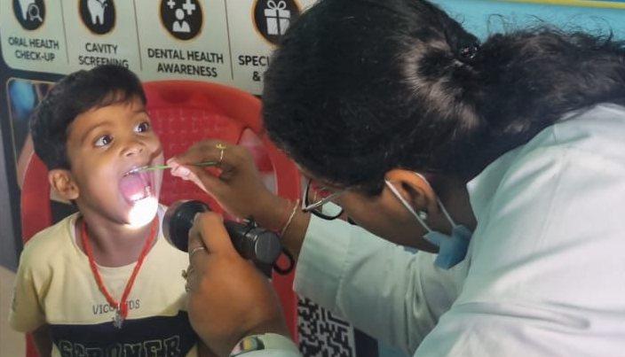 A White Oak dentist examining a student's teeth with a light during the dental camp at Sacred Child Academy, Ranchi