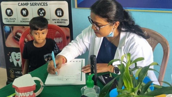 A White Oak dentist noting a student's cavity screening results at the Sacred Child Academy dental camp, Kokar